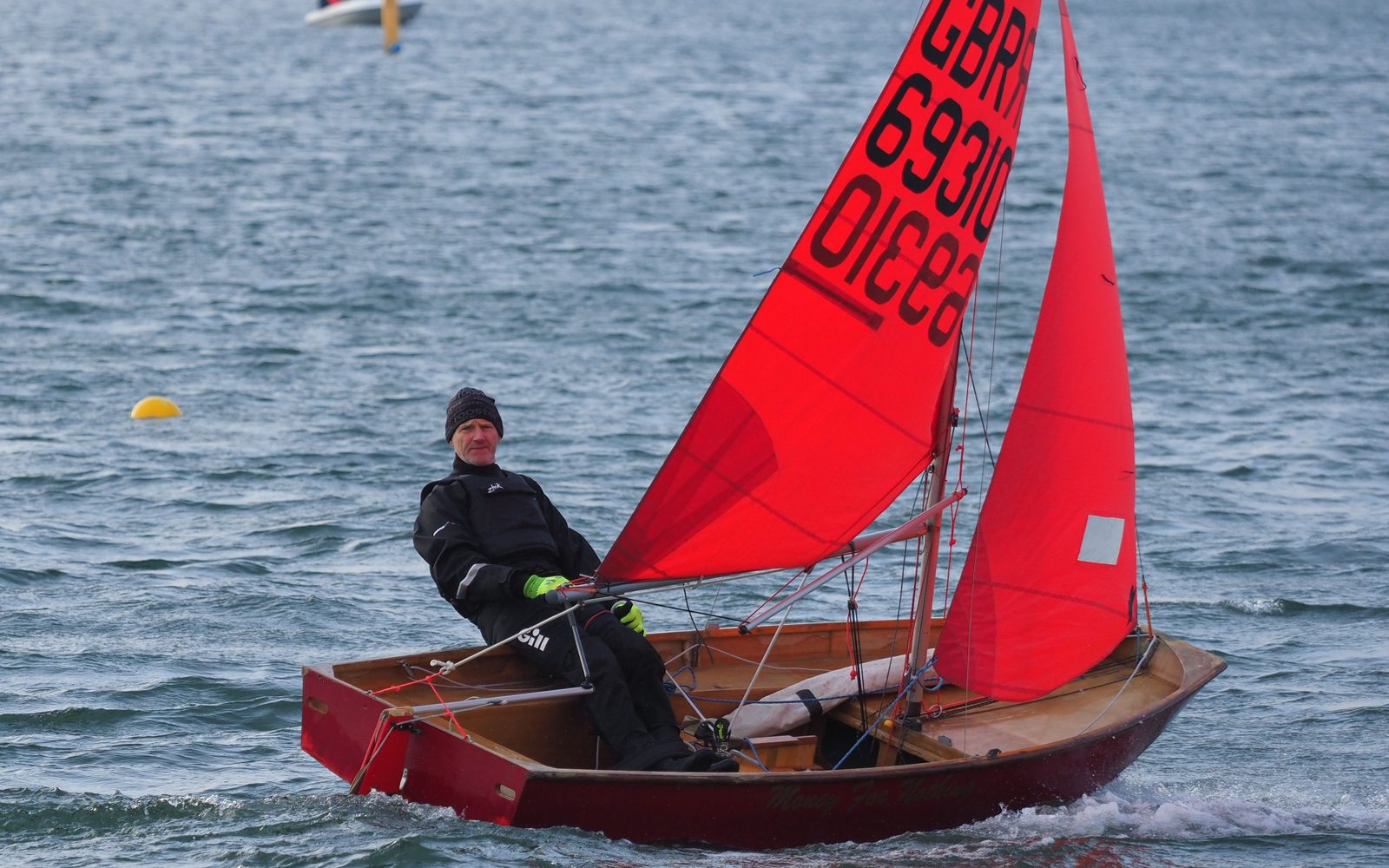 Mirror dinghy under red sails, helm sitting out