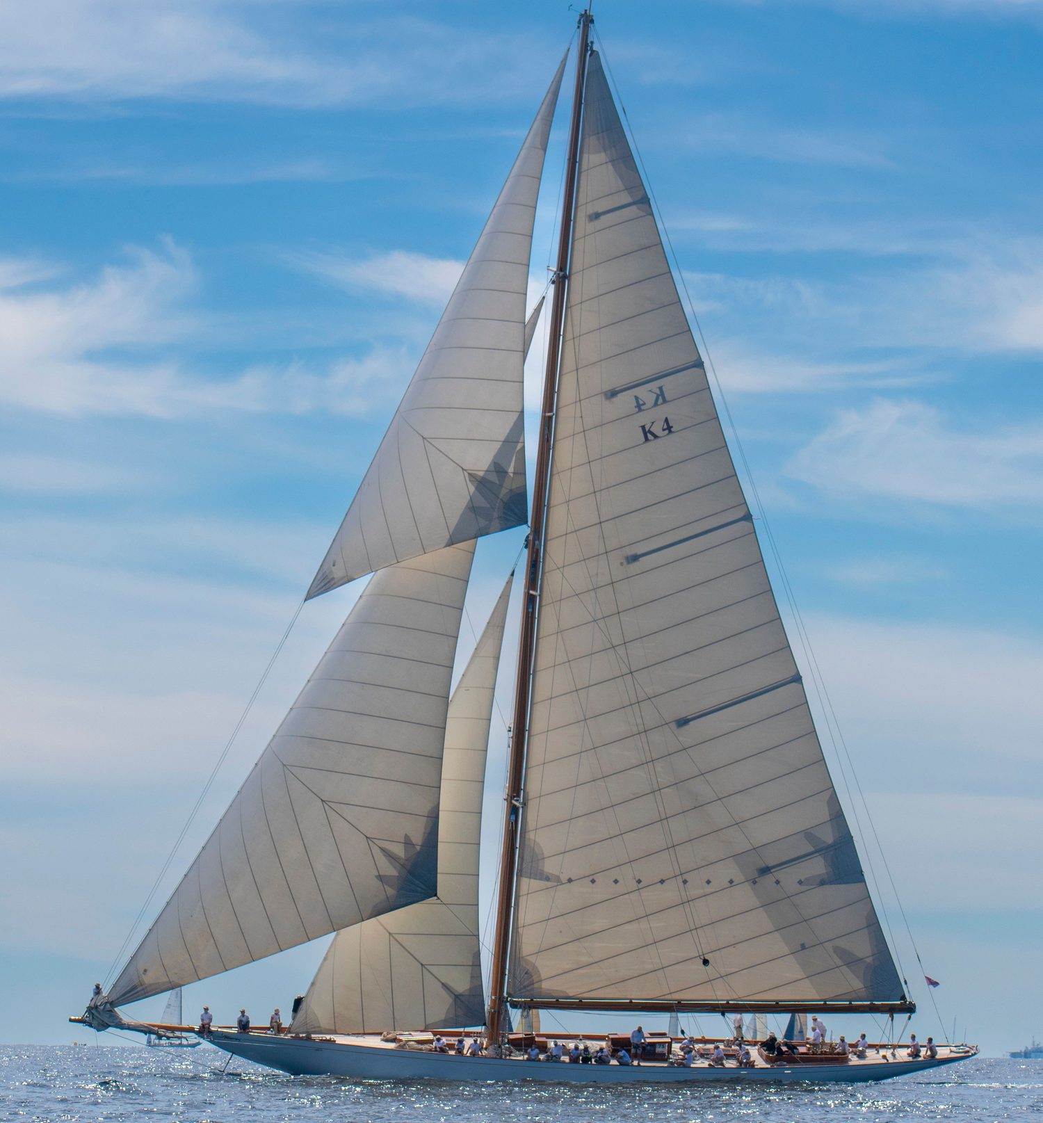 Classic superyacht cutter under full sail with a large crew working the deck