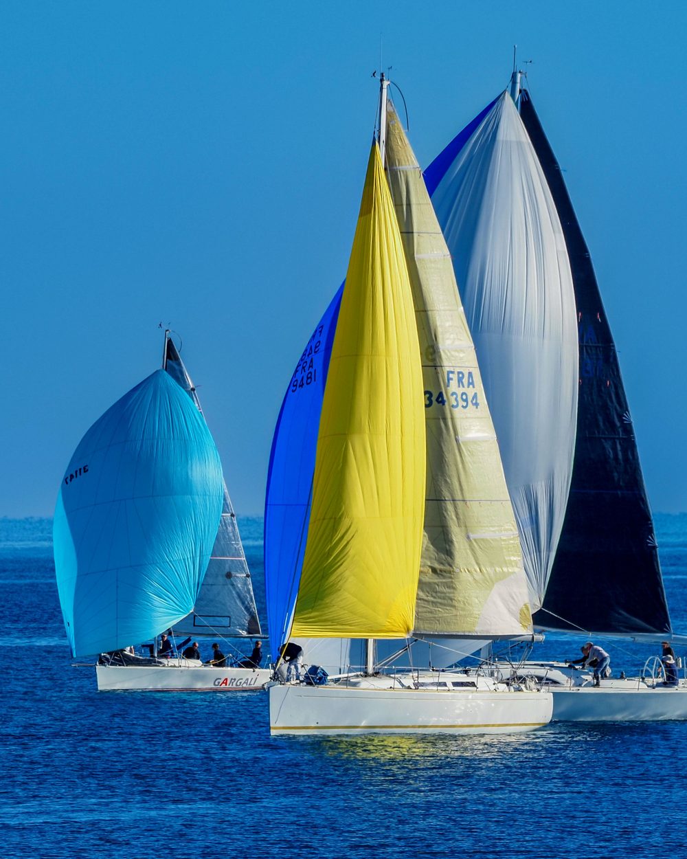 Three spinnakers side by side: turquoise, yellow and black