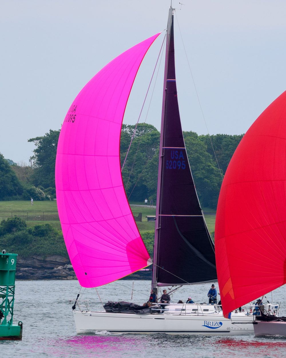 Two yachts downwind under hot pink and red asymmetric spinnakers